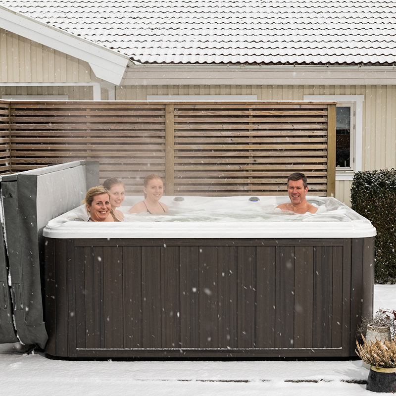 Familjen Milton i sitt spabad på vintern snötäckt altan